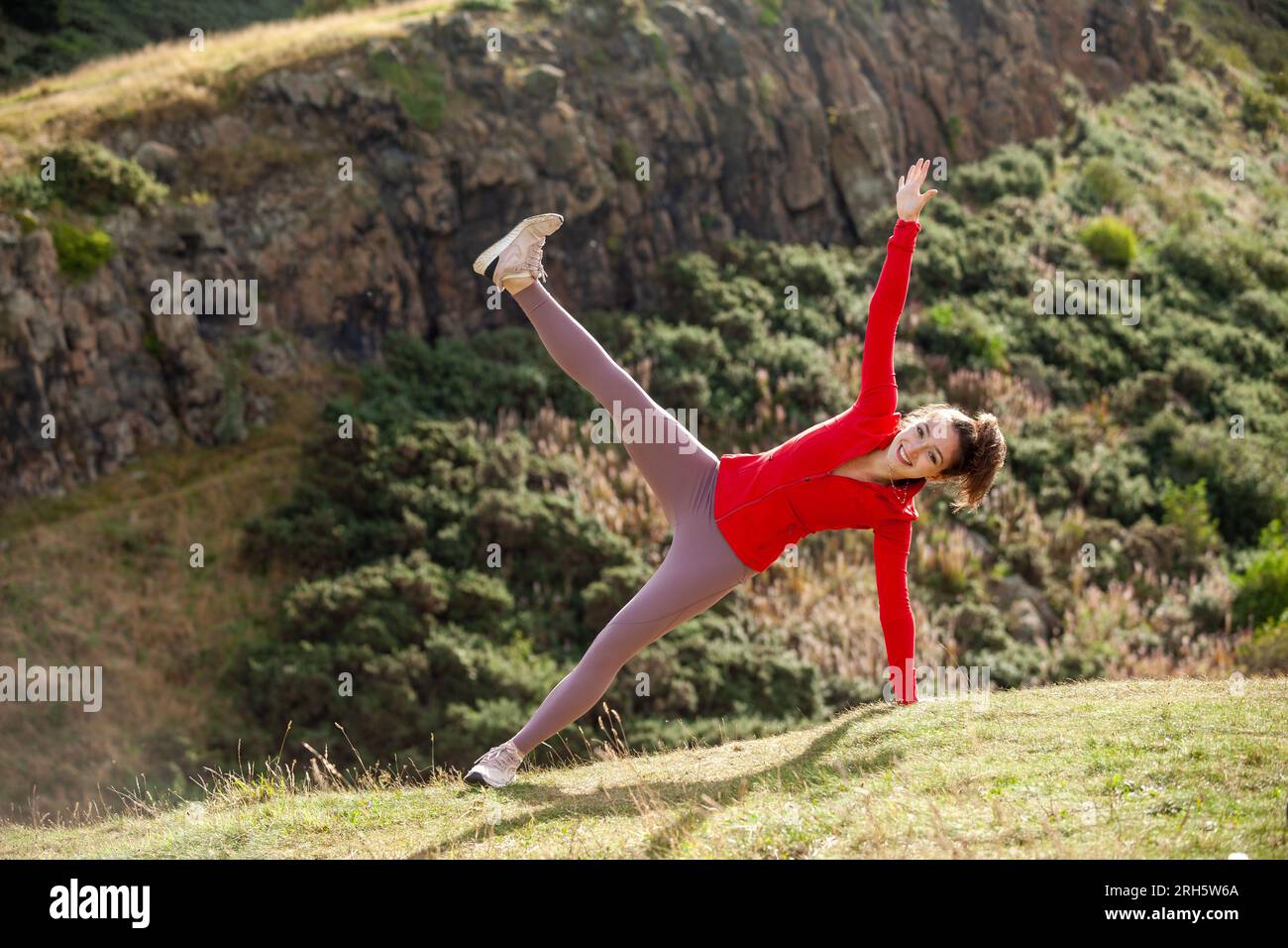A young woman wearing leggings stretching in a public park in Edinburgh Stock Photo