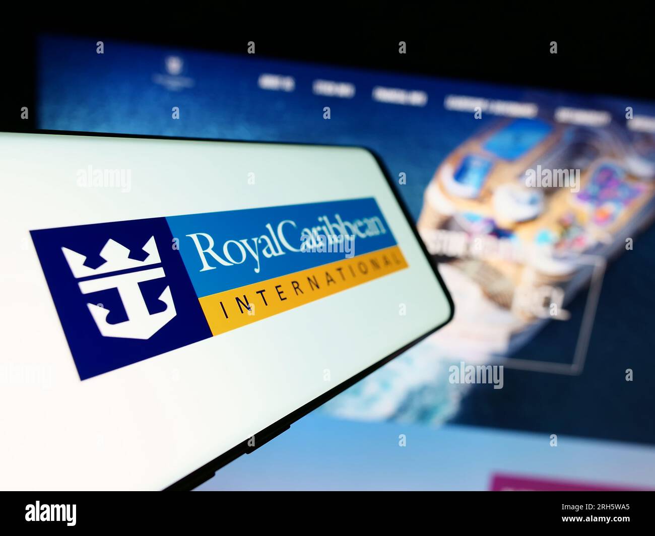 Cellphone with logo of company Royal Caribbean International (RCI) on screen in front of business website. Focus on center-left of phone display. Stock Photo