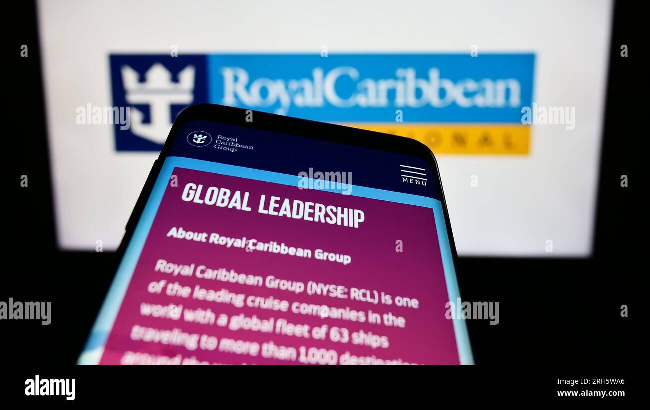 Mobile phone with website of company Royal Caribbean International (RCI) on screen in front of business logo. Focus on top-left of phone display. Stock Photo