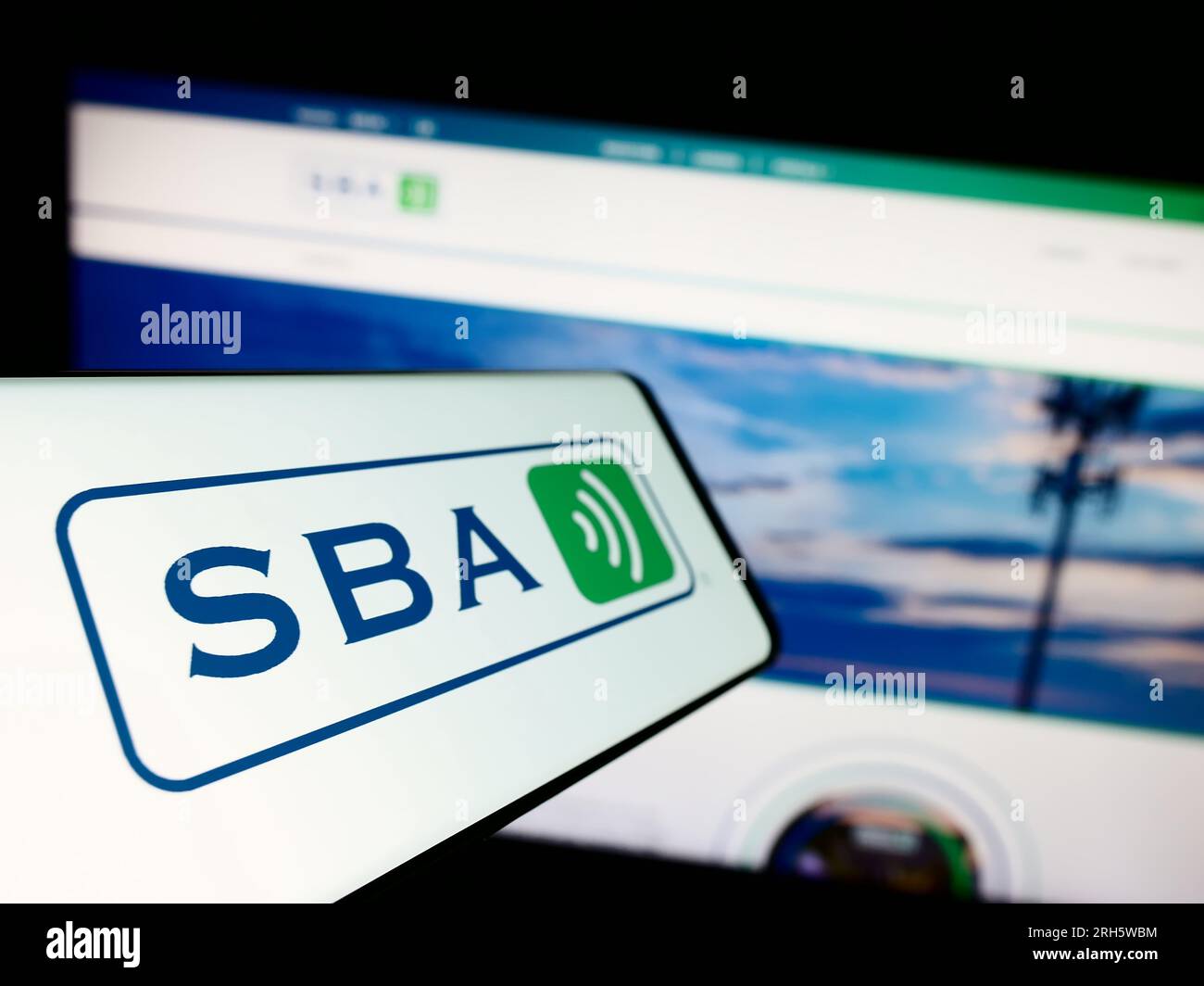 Smartphone with logo of American company SBA Communications Corporation on screen in front of business website. Focus on left of phone display. Stock Photo