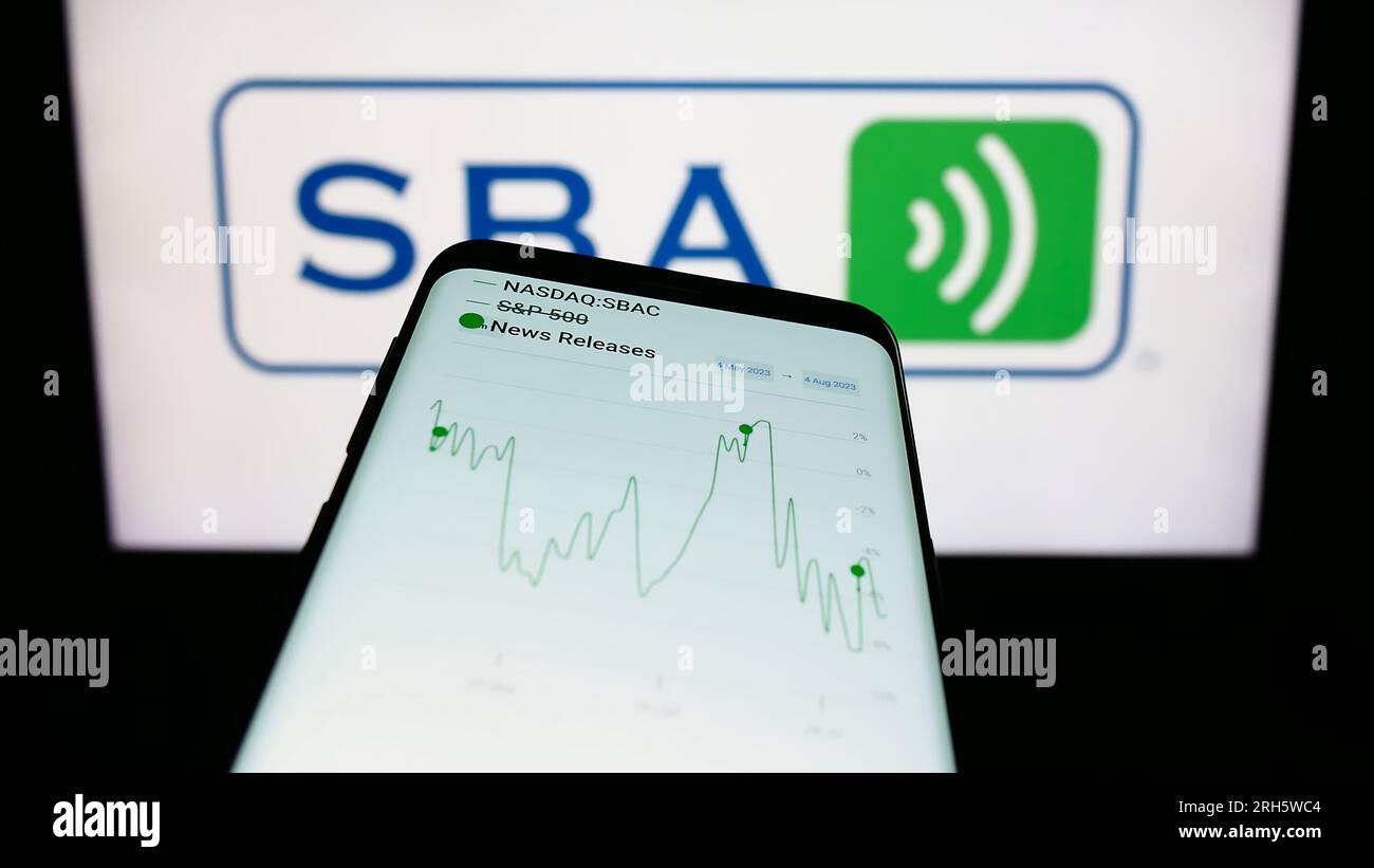 Mobile phone with website of US company SBA Communications Corporation on screen in front of business logo. Focus on top-left of phone display. Stock Photo
