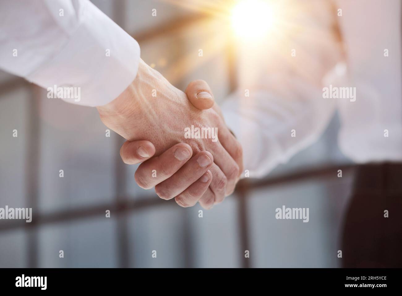 Two businessmen shake hands on the background of empty modern office, signing of a contract concept, close up Stock Photo