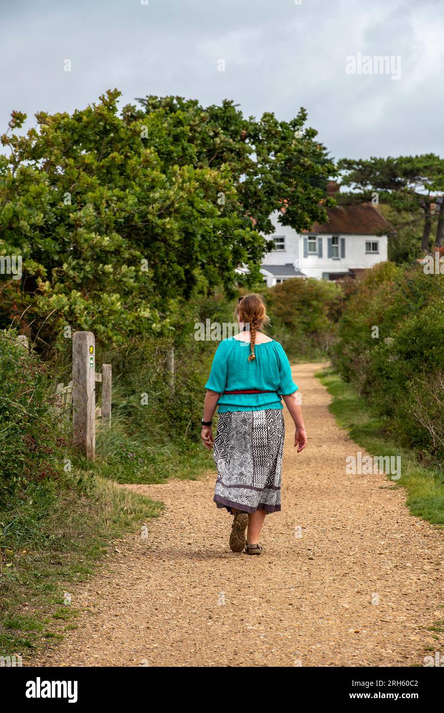 bohemian styled woman walking alone along a country lane enjoying the ...