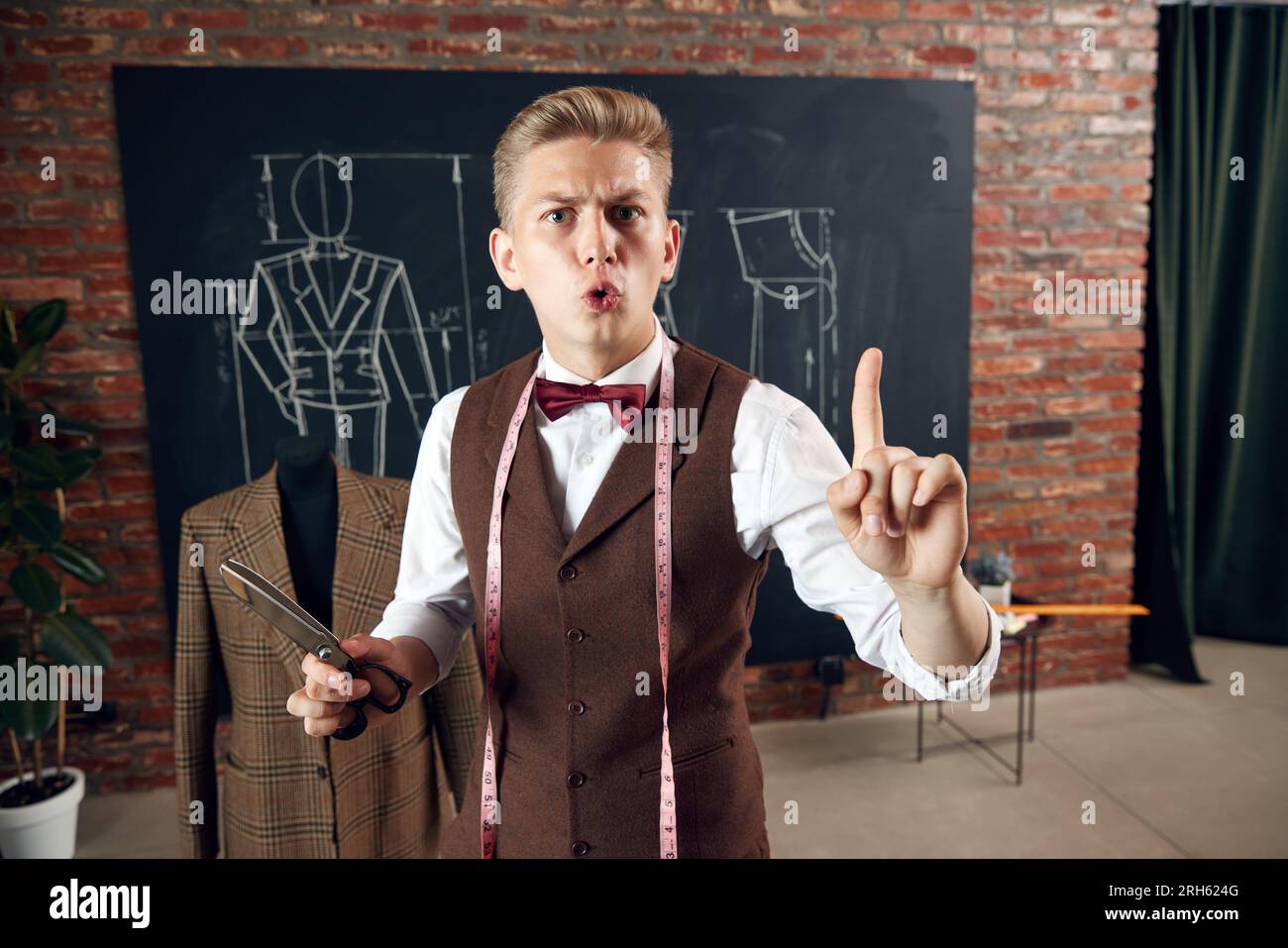 Young man, fashion designer with scissors and measuring tape raising ...