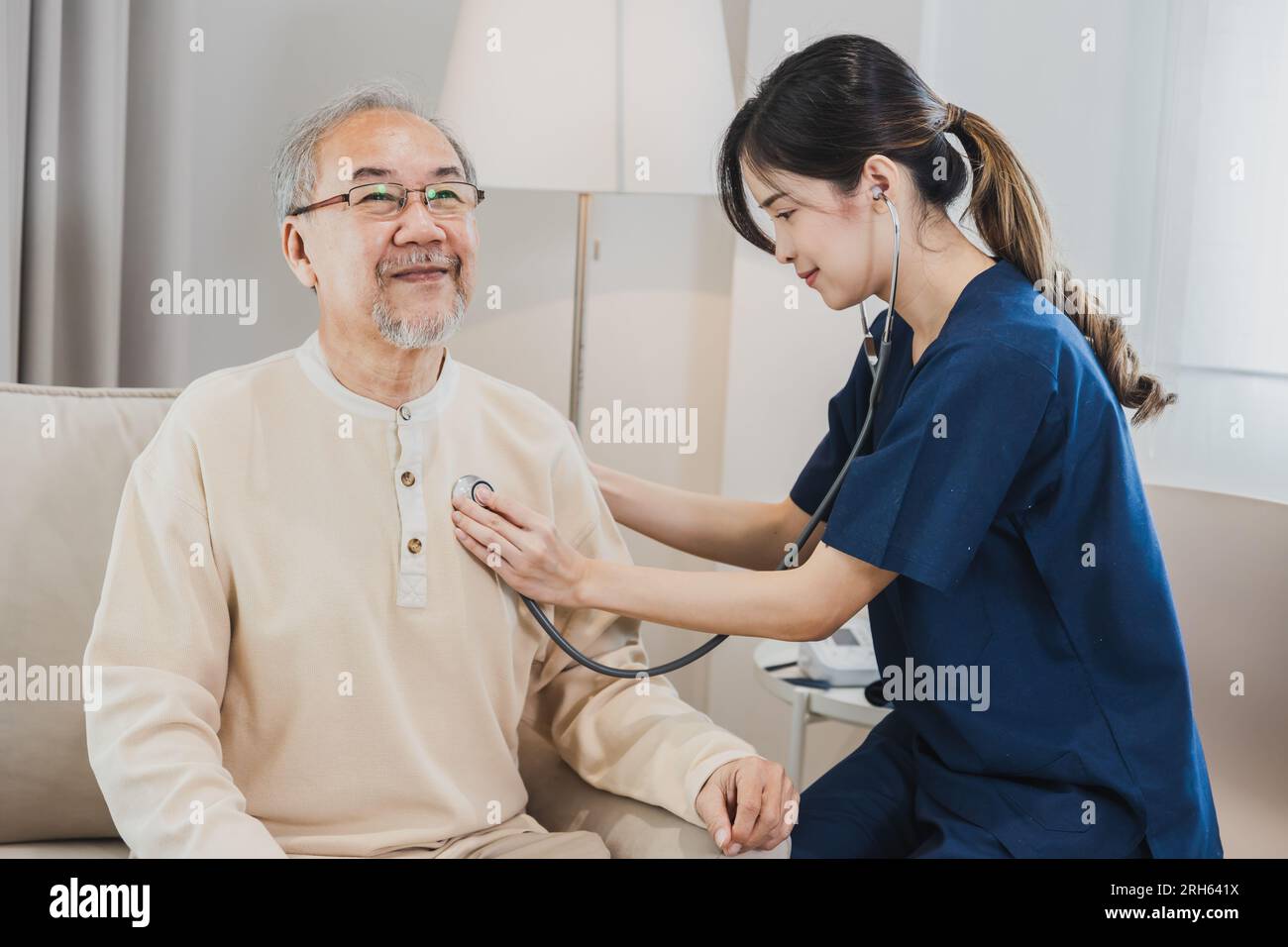 Asian nurse, doctor woman assisting checking heart rate stethoscope of Senior Asian patient man Stock Photo