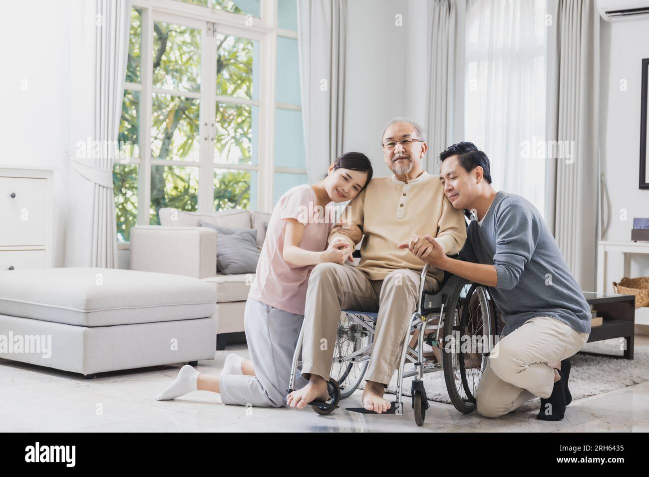 happy Asian family, senior man on wheelchair with daughter and son at home Stock Photo