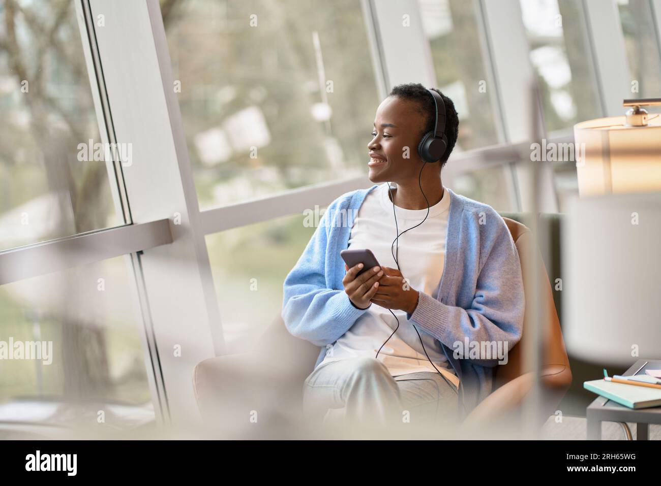 Happy African Black gen z girl wearing headphones using smartphone ...