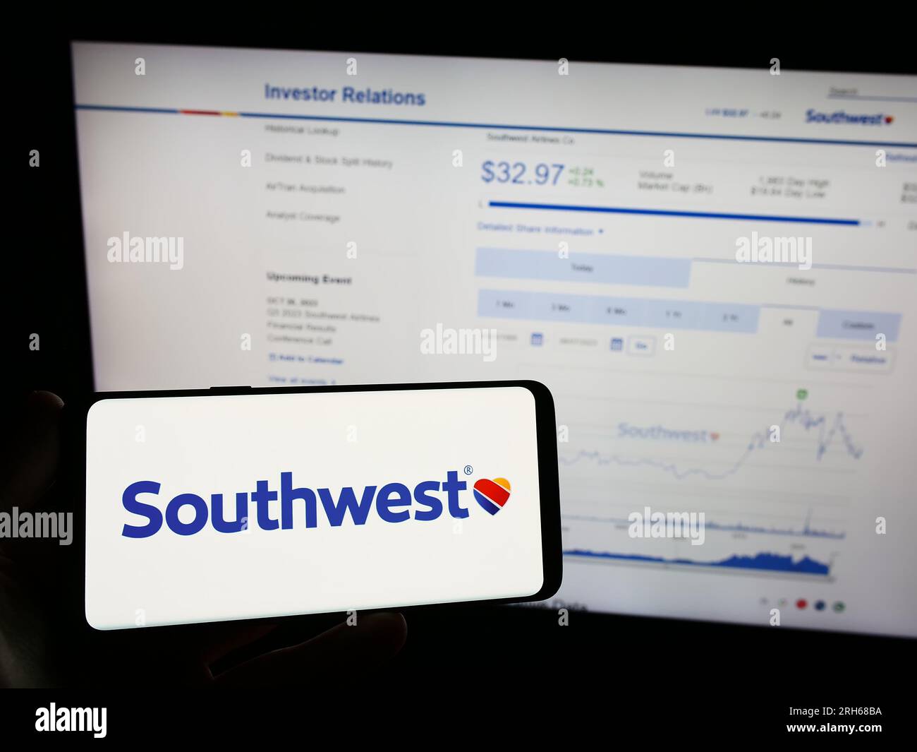Person holding mobile phone with logo of American airline company Southwest Airlines Co. on screen in front of web page. Focus on phone display. Stock Photo