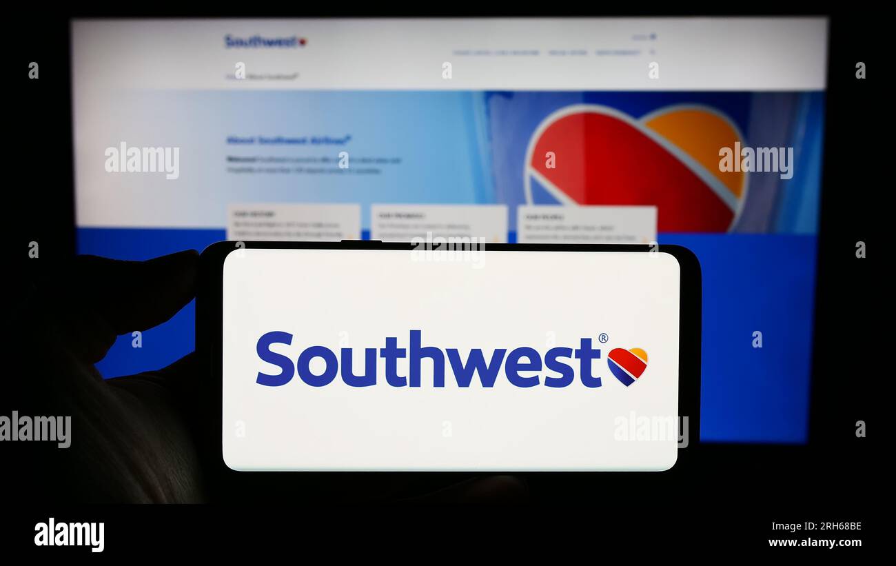 Person holding smartphone with logo of US airline company Southwest Airlines Co. on screen in front of website. Focus on phone display. Stock Photo