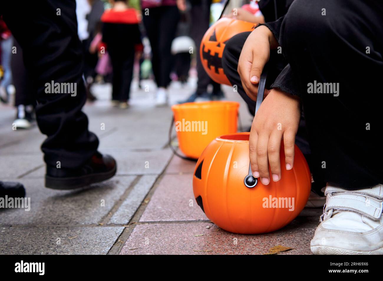 Kids sitting on the street with pumpkin baskets at Halloween Trick or ...