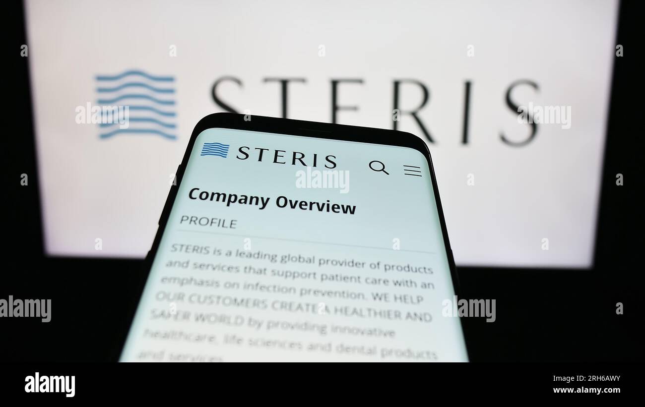 Mobile phone with webpage of medical equipment company Steris plc on screen in front of business logo. Focus on top-left of phone display. Stock Photo