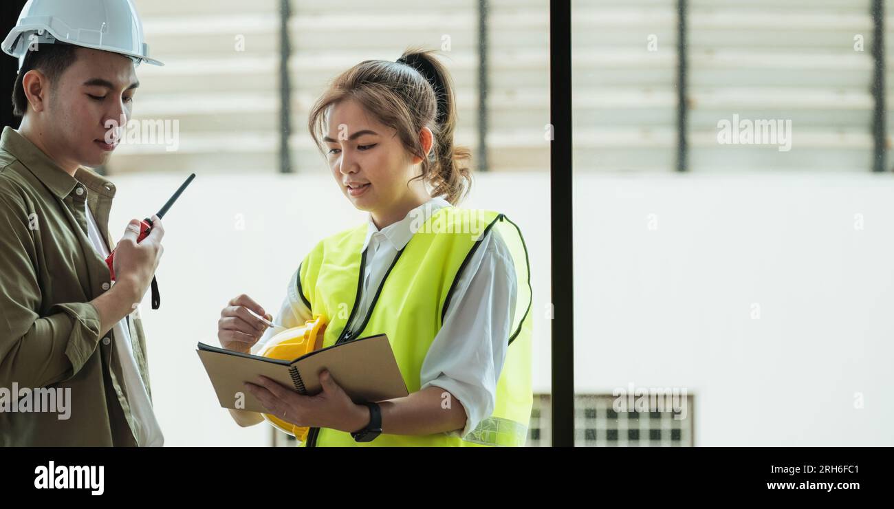 Young architect and engineer colleague workers working discussion, meeting and analyzing blueprint at construction site Stock Photo