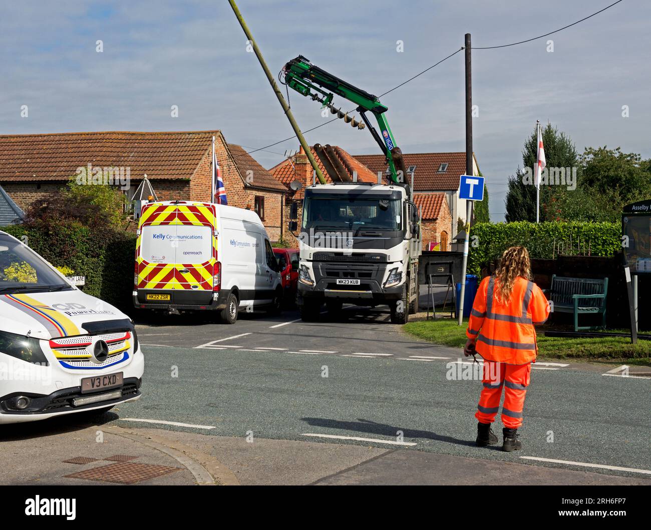 Contractors replacing telegraph poles and wiring in a village, England