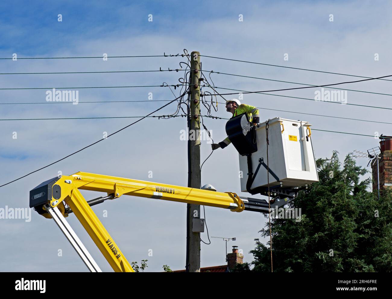 Contractors replacing telegraph poles and wiring in a village, England