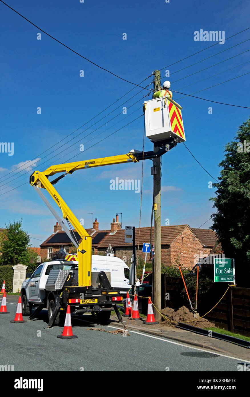 Contractors replacing telegraph poles and wiring in a village, England