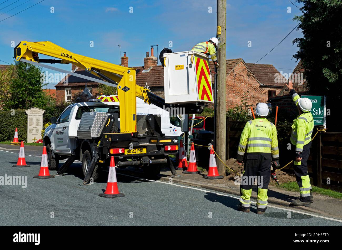 Contractors replacing telegraph poles and wiring in a village, England