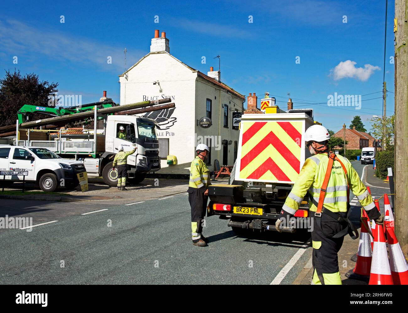 Contractors replacing telegraph poles and wiring in a village, England