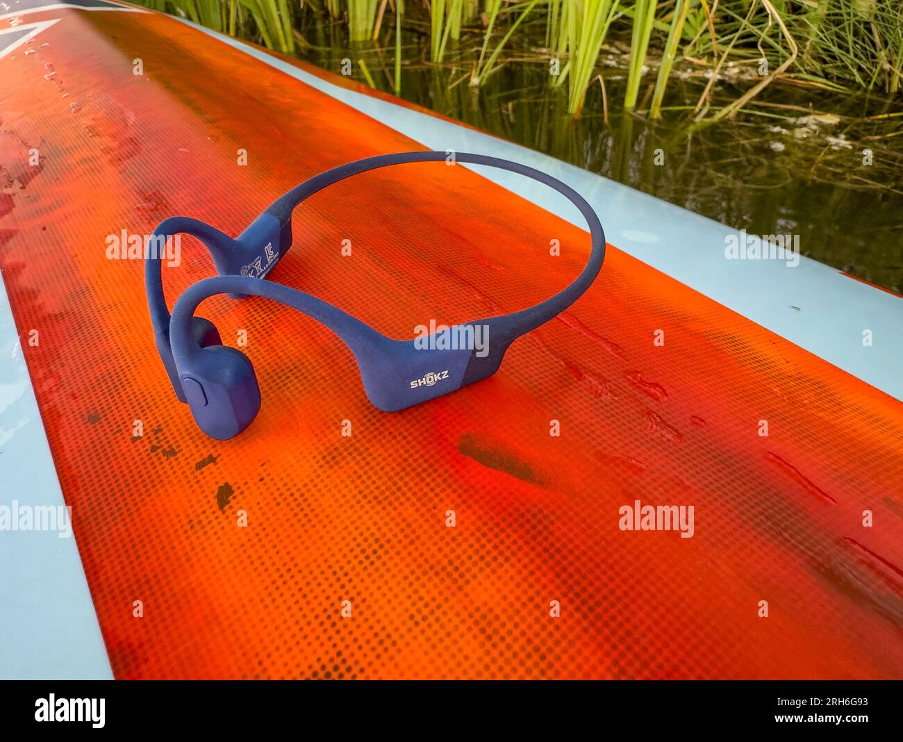 Fort Collins, CO, USA - July 23: SHOKZ OpenRun, open-ear bluetooth bone conduction sport headphones on a deck of stand up paddleboard. Stock Photo