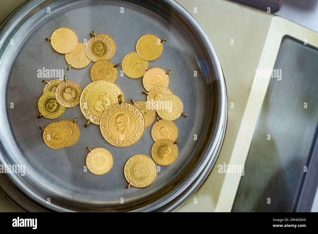 Stack of full, half and quarter Turkish gold coins on precision jeweler's scale Stock Photo
