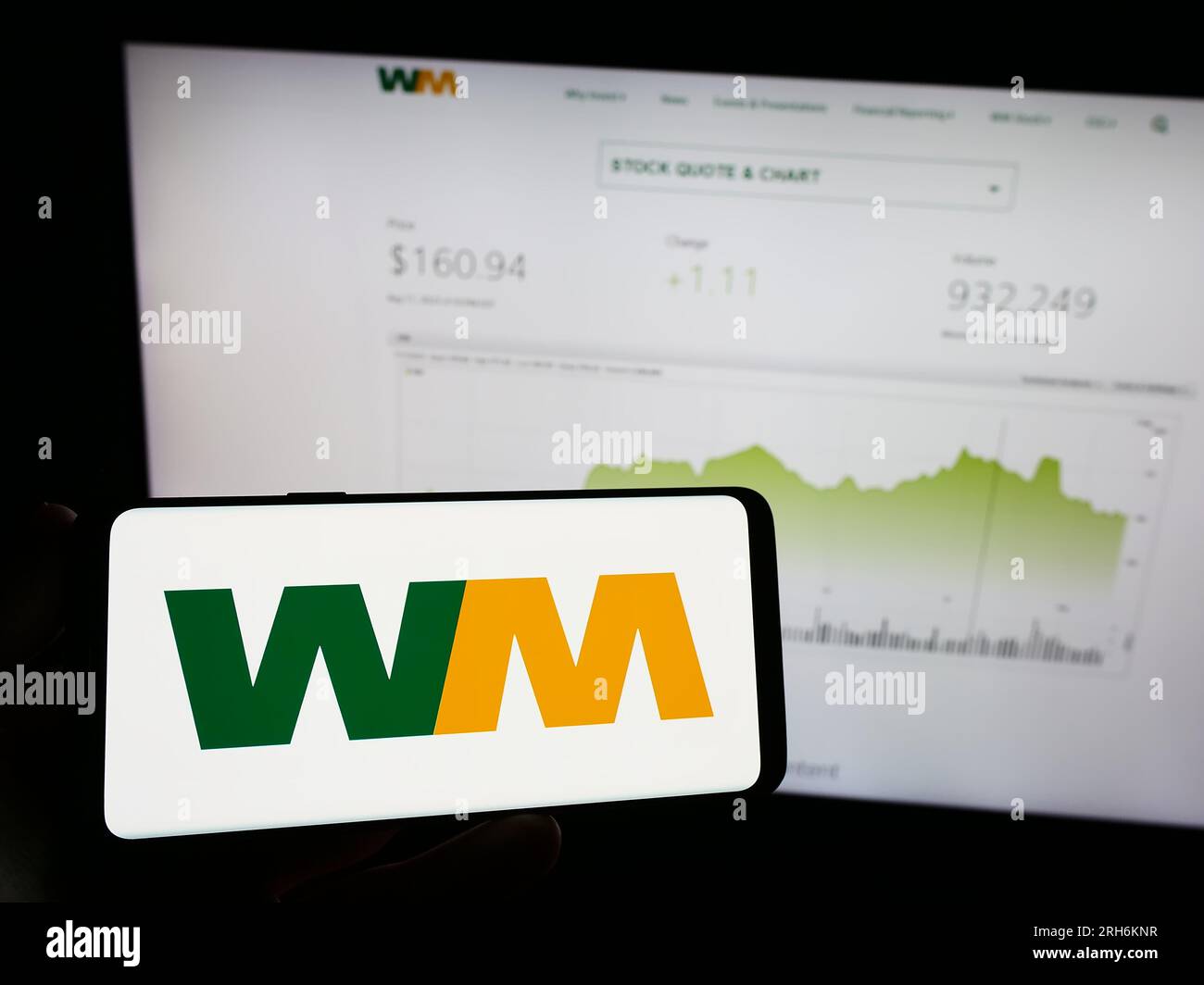Person holding mobile phone with logo of American disposal company Waste Management Inc. on screen in front of web page. Focus on phone display. Stock Photo