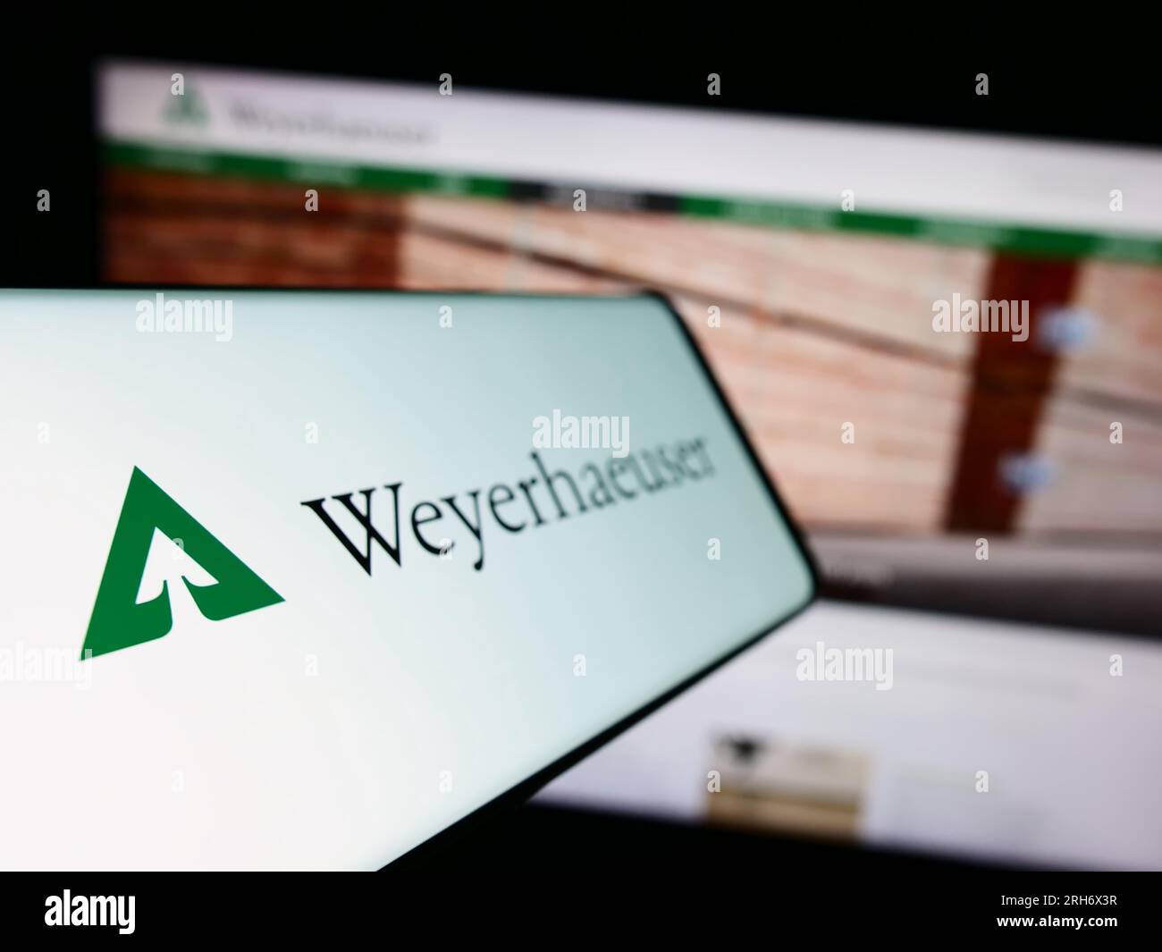 Cellphone with logo of US timberland business Weyerhaeuser Company on screen in front of business website. Focus on left of phone display. Stock Photo