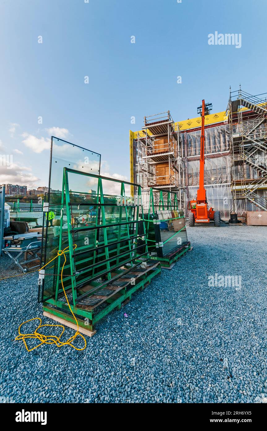 An orange rental highlift with its arm extended to roof of building at