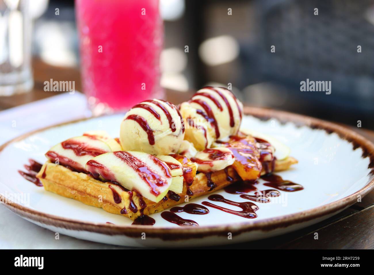 Belgian waffle with ice cream, berry sauce and fresh sliced fruits on a ...