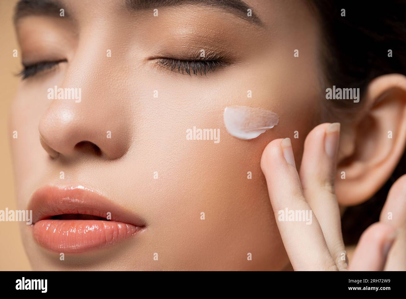 Close up view of young asian woman with perfect skin applying face