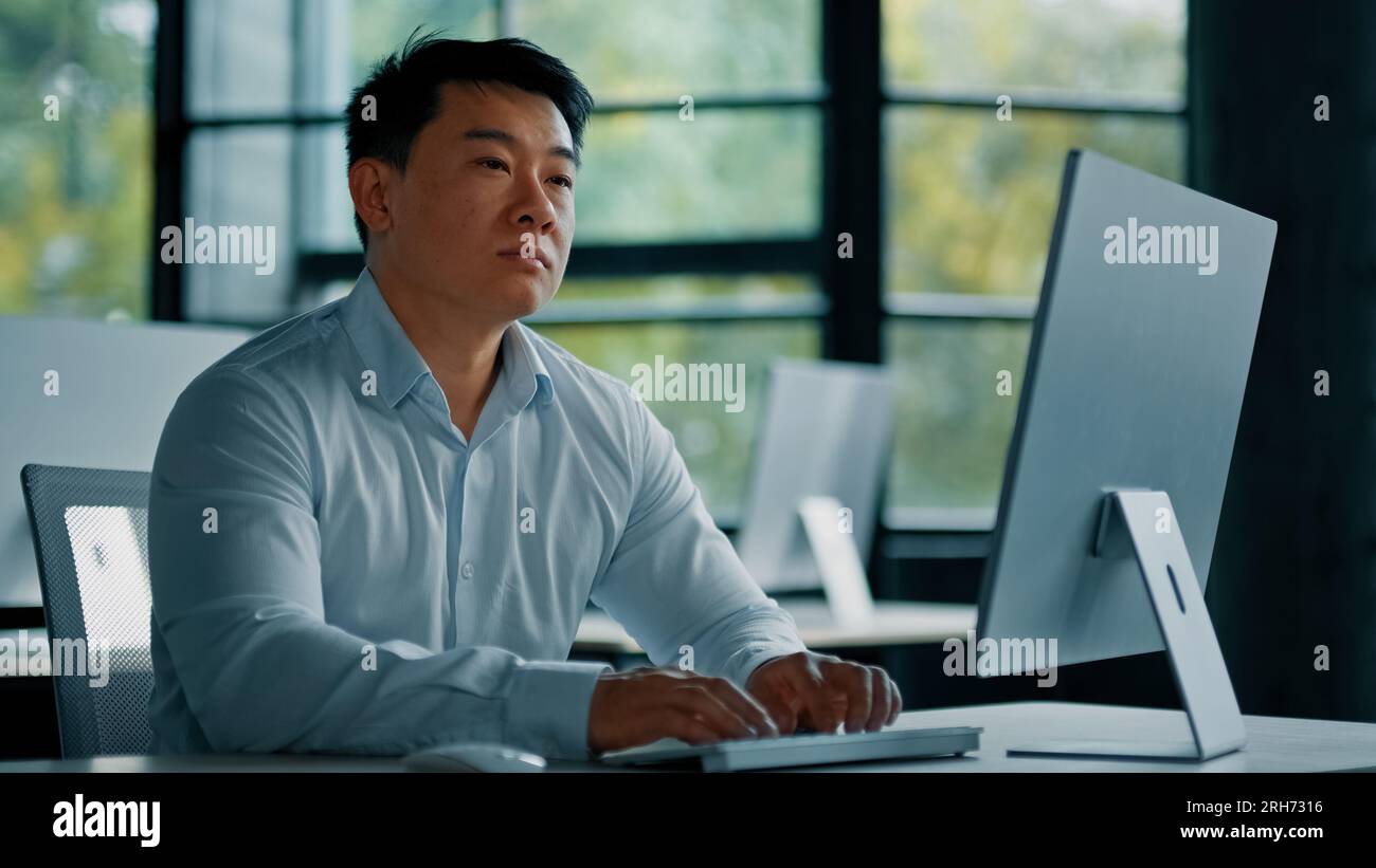 Thoughtful asian korean chinese ceo businessman dreamer smart japanese man guy sit at office desk planning business plan think idea in mind create Stock Photo