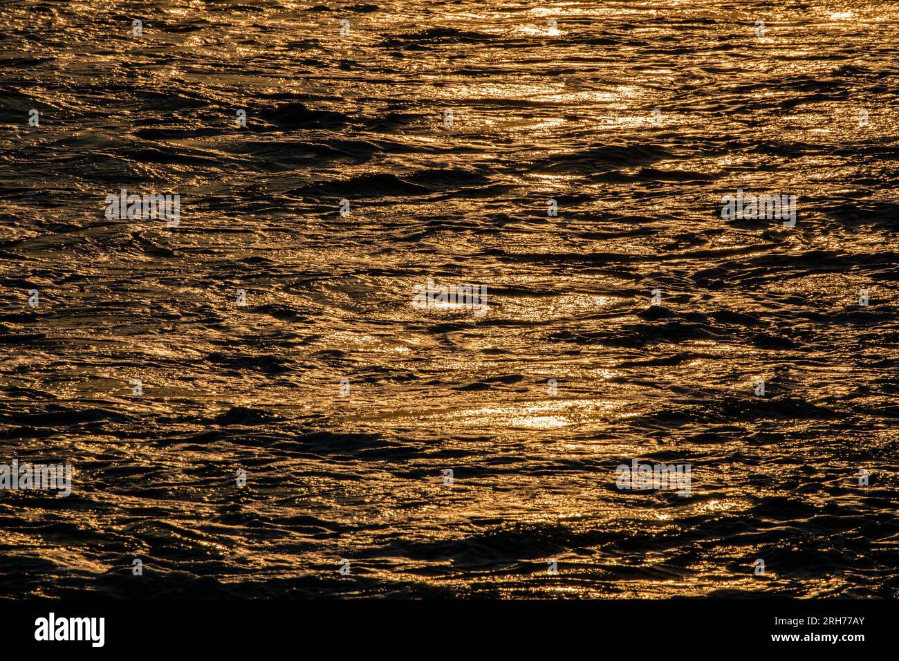 Sun shimmering on the ocean waves at sunset creating a beautiful abstract background Stock Photo