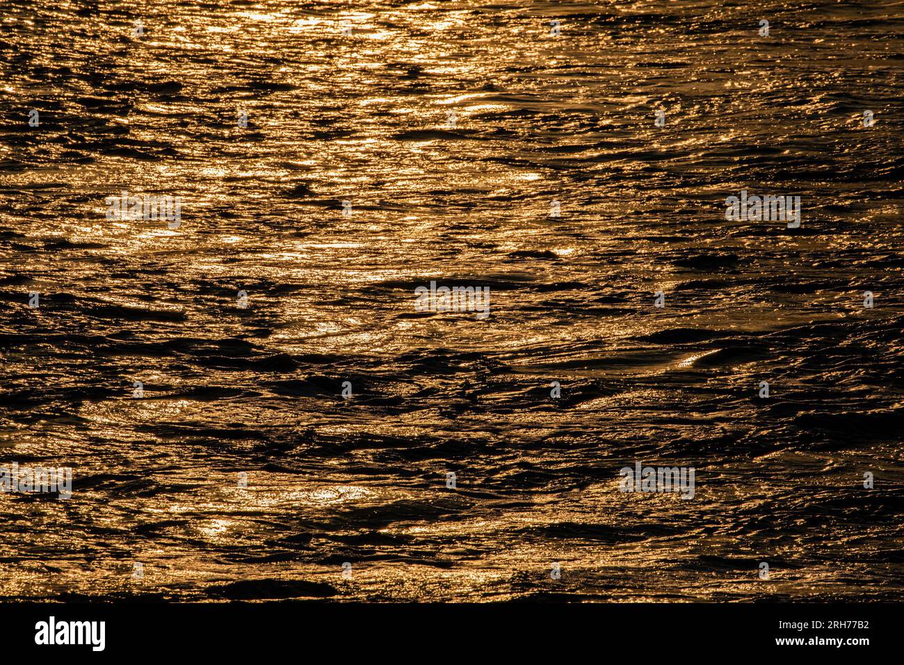 Sun shimmering on the ocean waves at sunset creating a beautiful abstract background Stock Photo