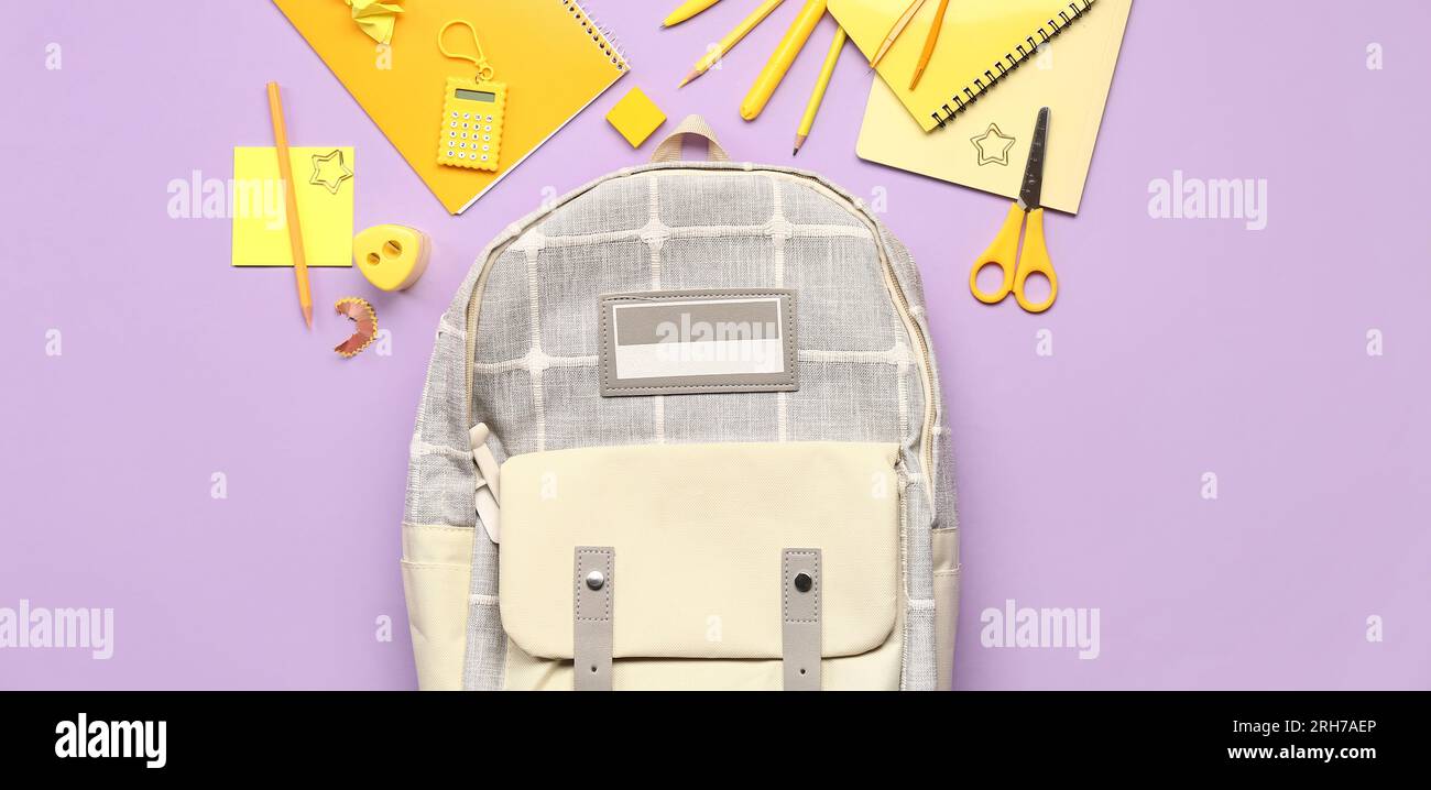 School backpack and different stationery on lilac background, top view Stock Photo