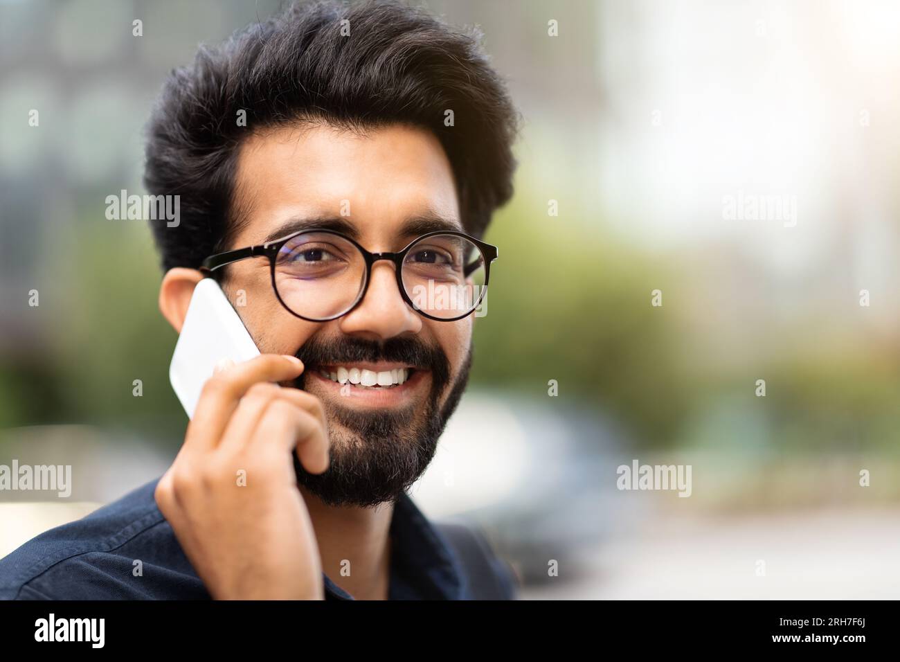 Portrait of cheerful young indian businessman talking on phone Stock Photo