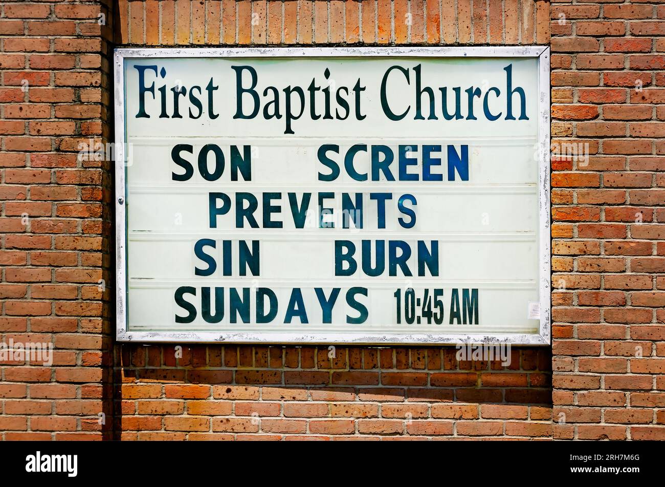 A sign at First Baptist Church of Chickasaw reminds passersby that while the American South is experiencing a heatwave, son screen prevents sin burn. Stock Photo