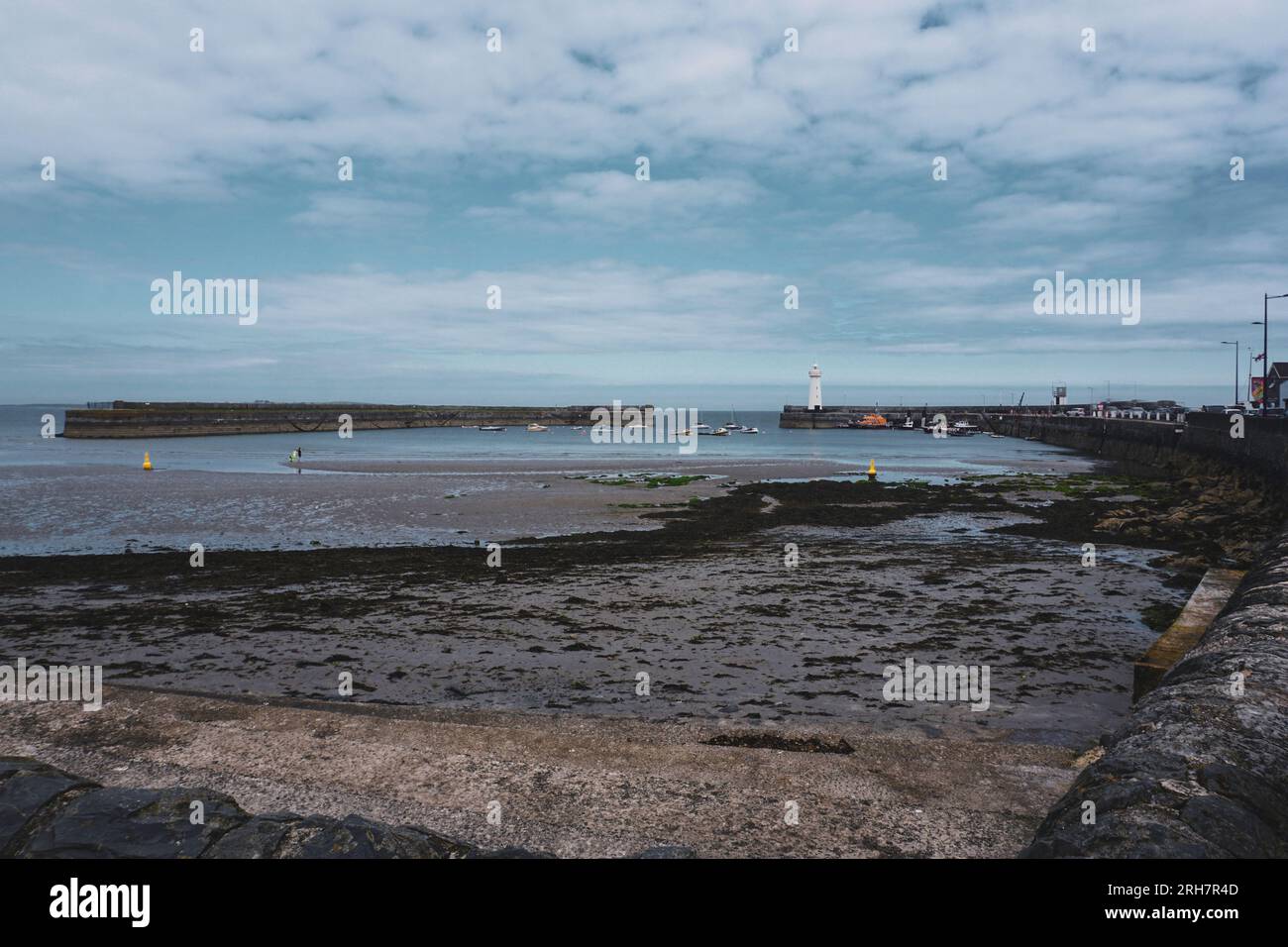 The beachfront in Donaghadee, County Down, Northern Ireland with the well known landmark white lighthouse in the distance. Stock Photo