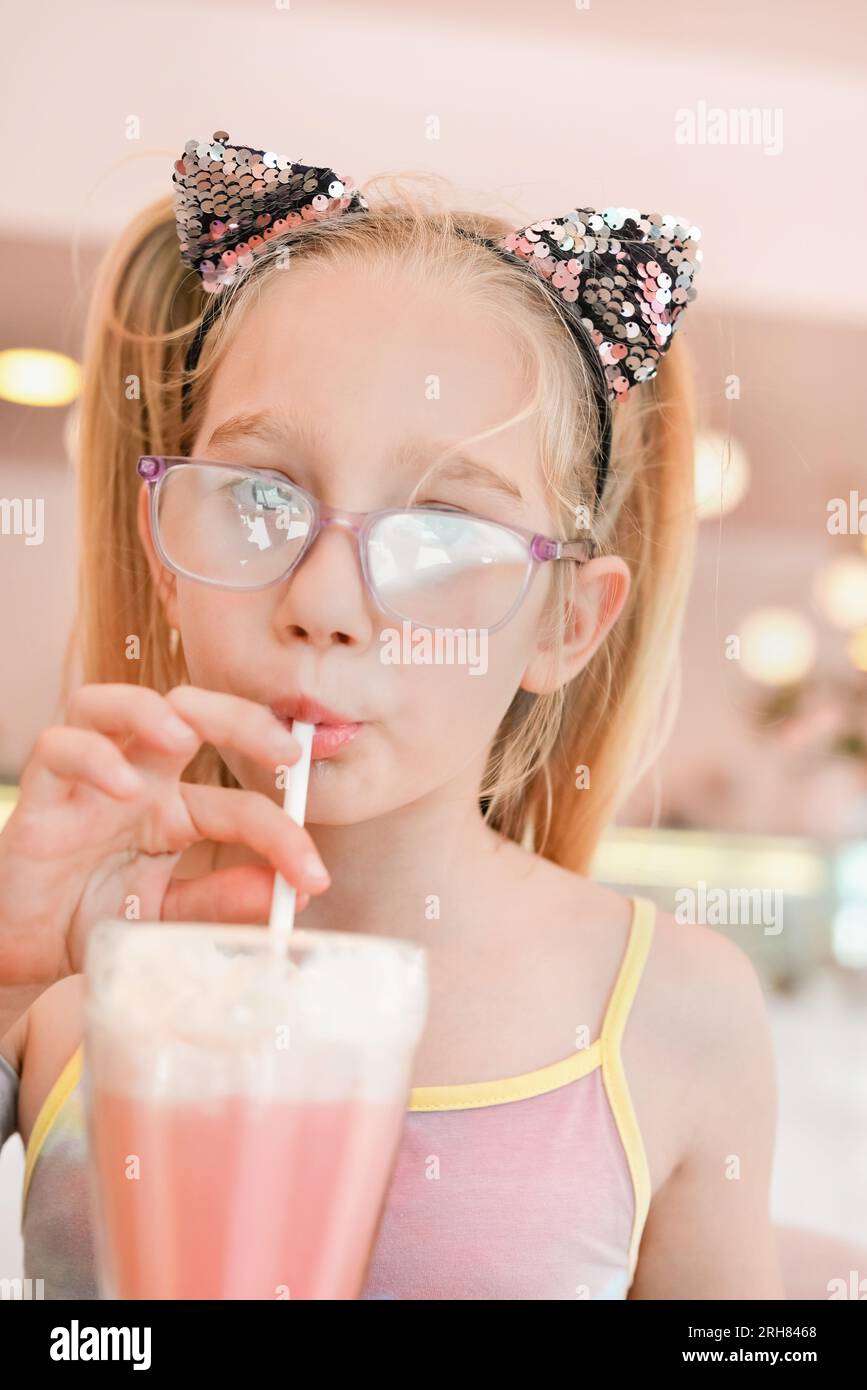 Little pretty girl seven years old drinking strawberry milkshake ...