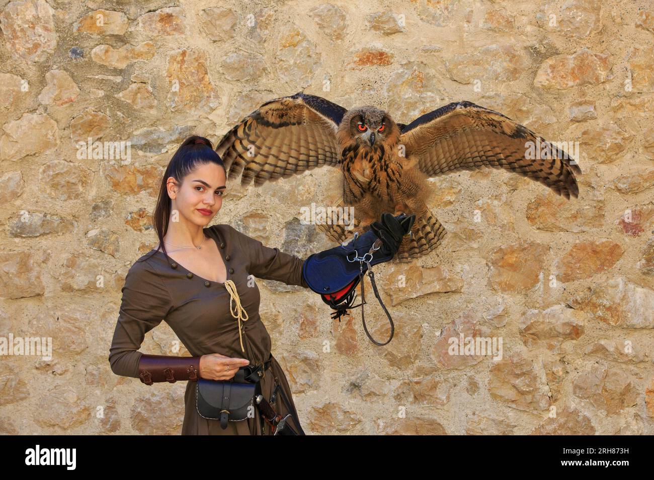 A female falconer holding a young Eurasian eagle-owl with big beautiful orange eyes at Golubac Fortress in Golubac, Serbia Stock Photo