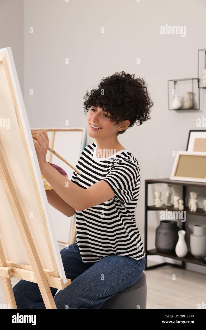 Young woman painting on easel with canvas in studio Stock Photo - Alamy