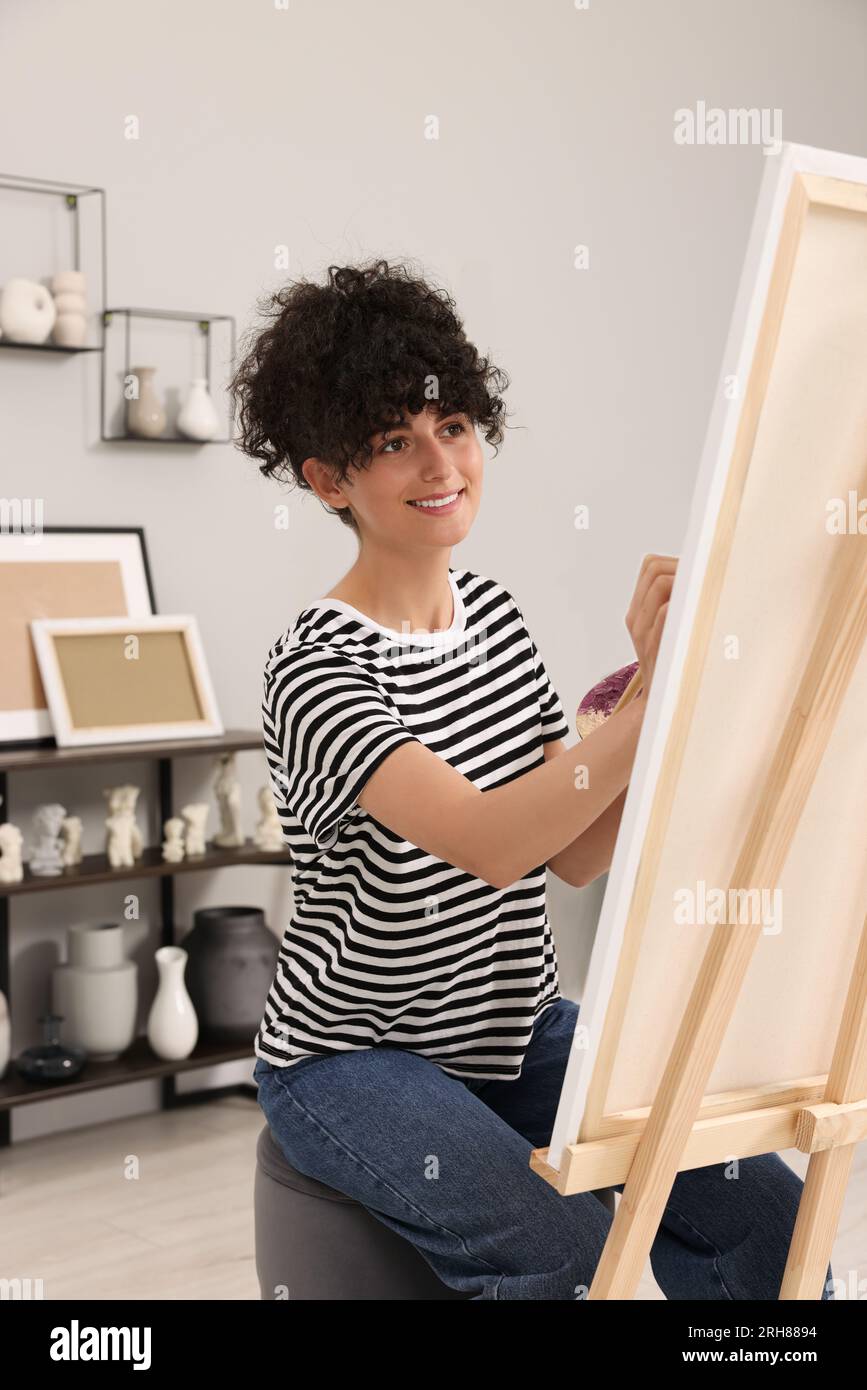 Young woman painting on easel with canvas in studio Stock Photo - Alamy