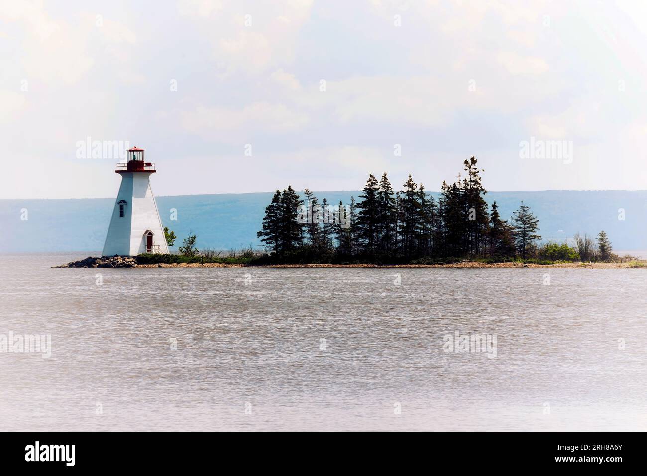 Artistic, atmospheric shot of lighthouse and row of trees in daylight Stock Photo