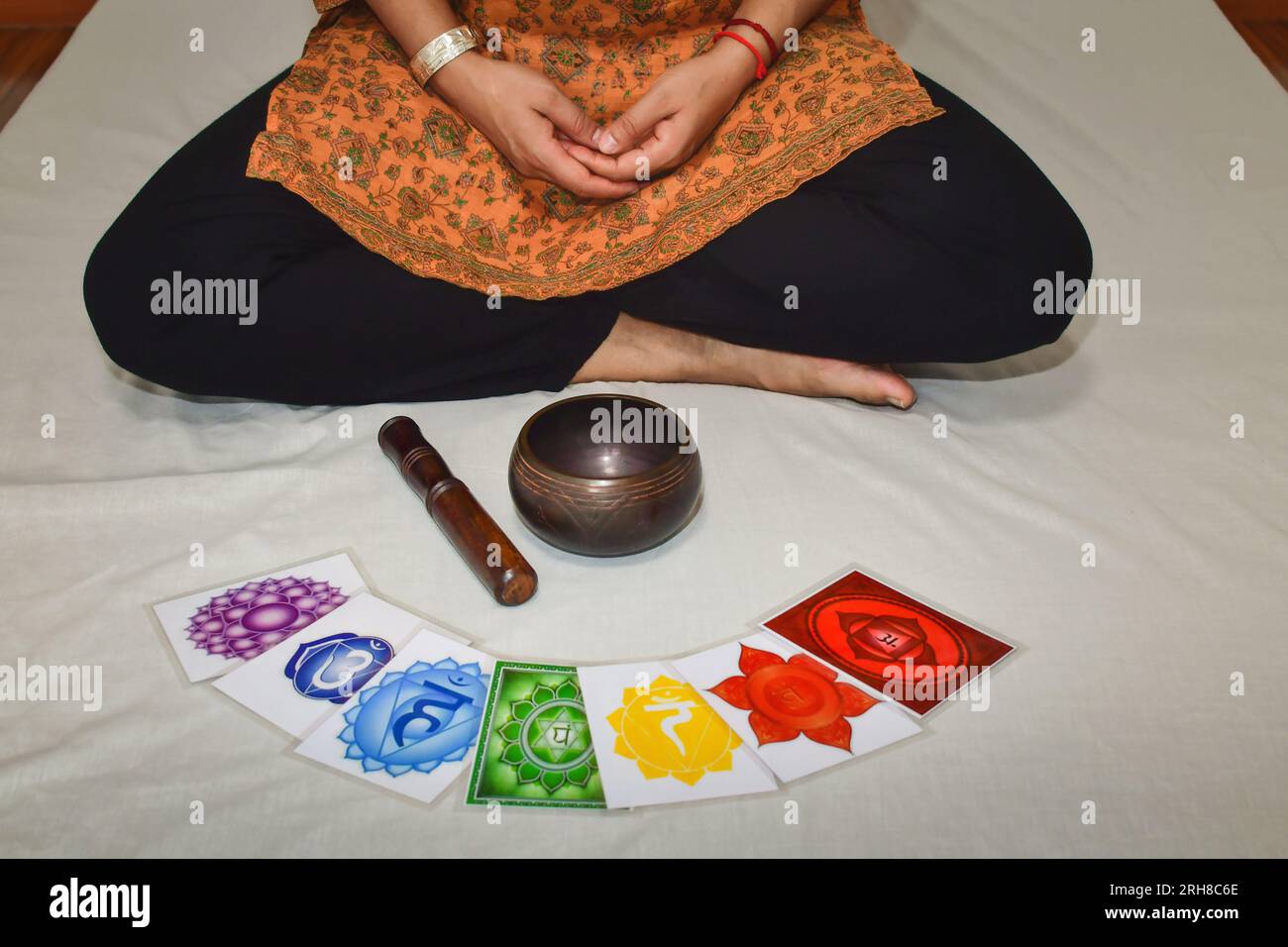 A woman practicing meditation and healing with a Tibetan singing bowl. Human body 7 Chakras energy system pictures, yoga meditation. Stock Photo
