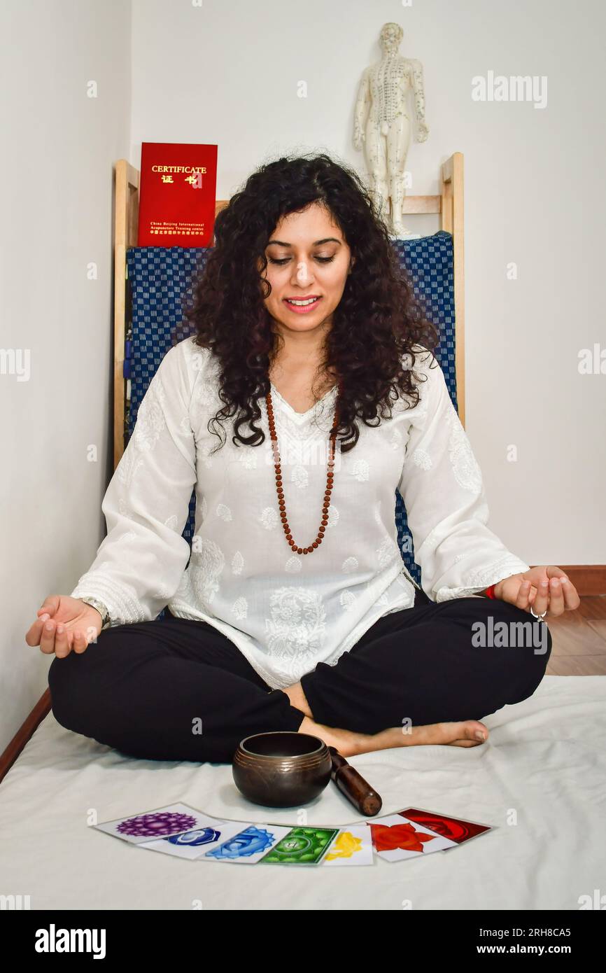 A woman practicing meditation and healing with a Tibetan singing bowl. Stock Photo