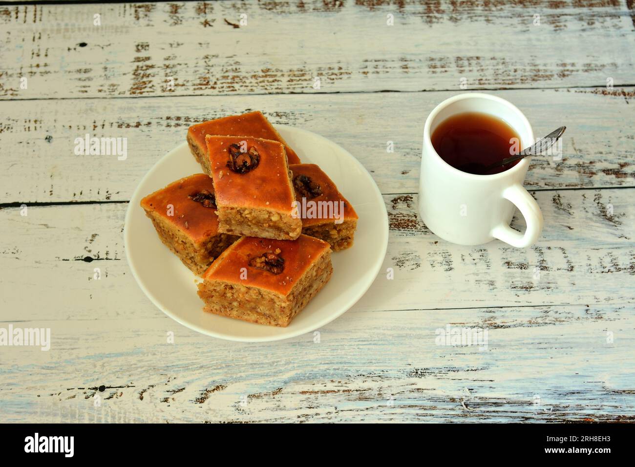Delicious fresh baklava, a plate with oriental sweets and a cup of hot tea on a light wooden table. Close-up. Stock Photo