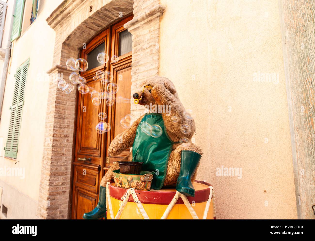 Antibes France - May 1 2011; Person dressed in bear costume sitting on drum blowing bubbles Stock Photo