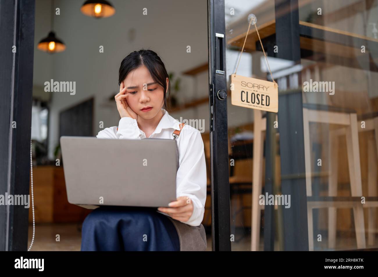 A stressed Asian female coffee shop or restaurant owner feels