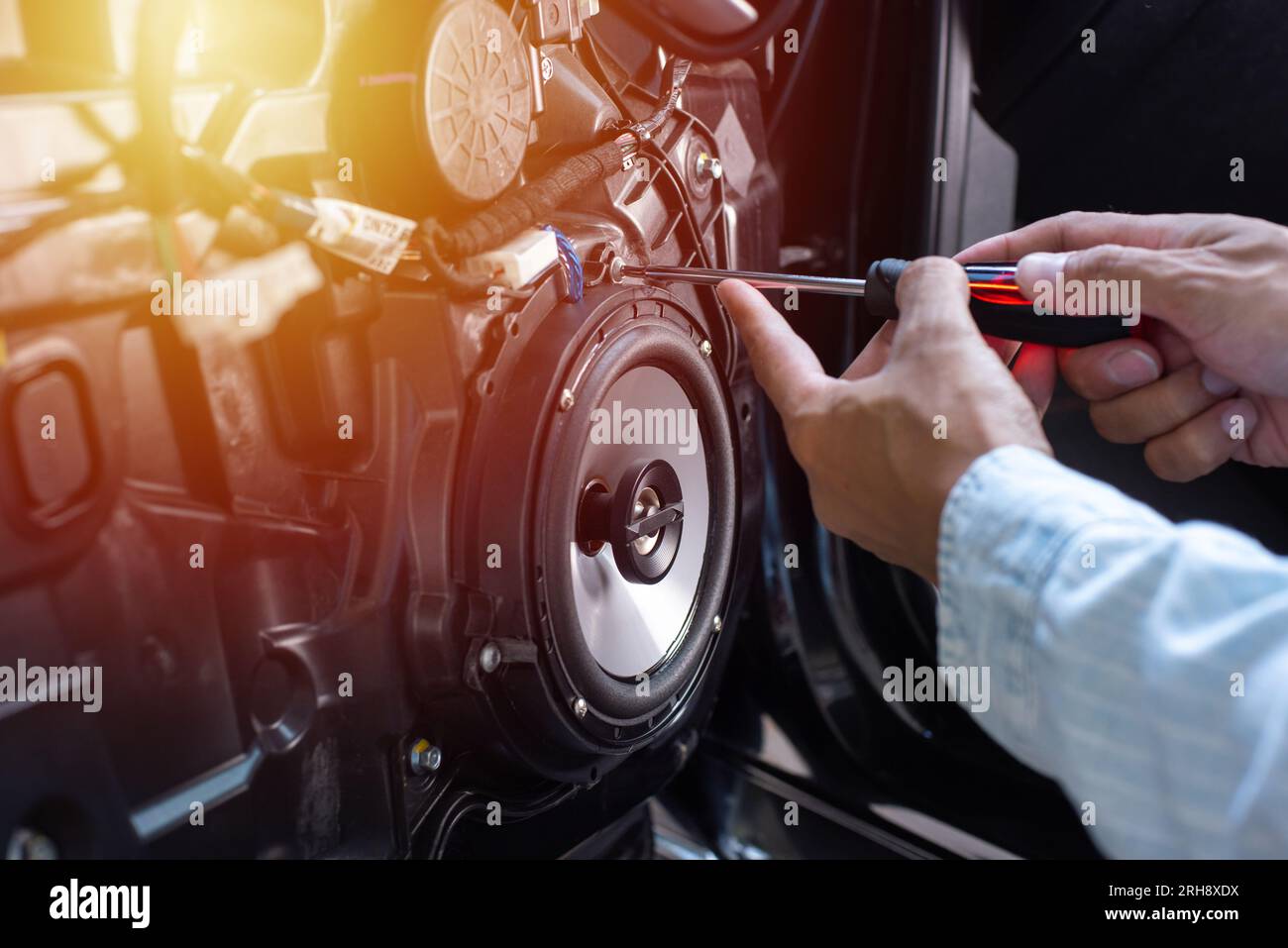 Technician installing the car speaker to the car door. Car audio installation concept. Stock Photo