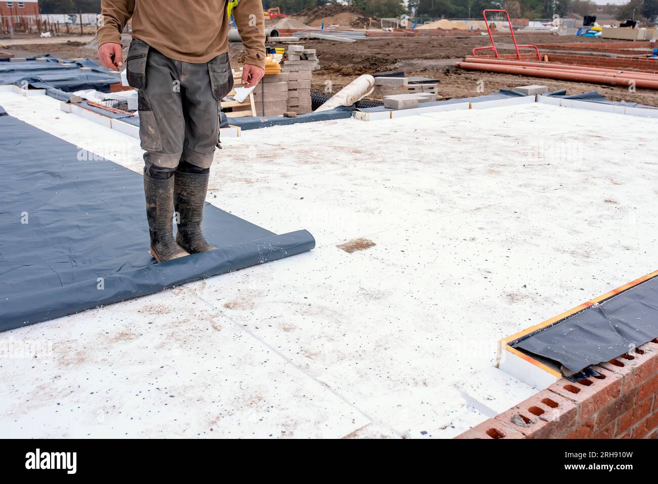 Builder placing polystyrene insulation boards on waterproofing membrane