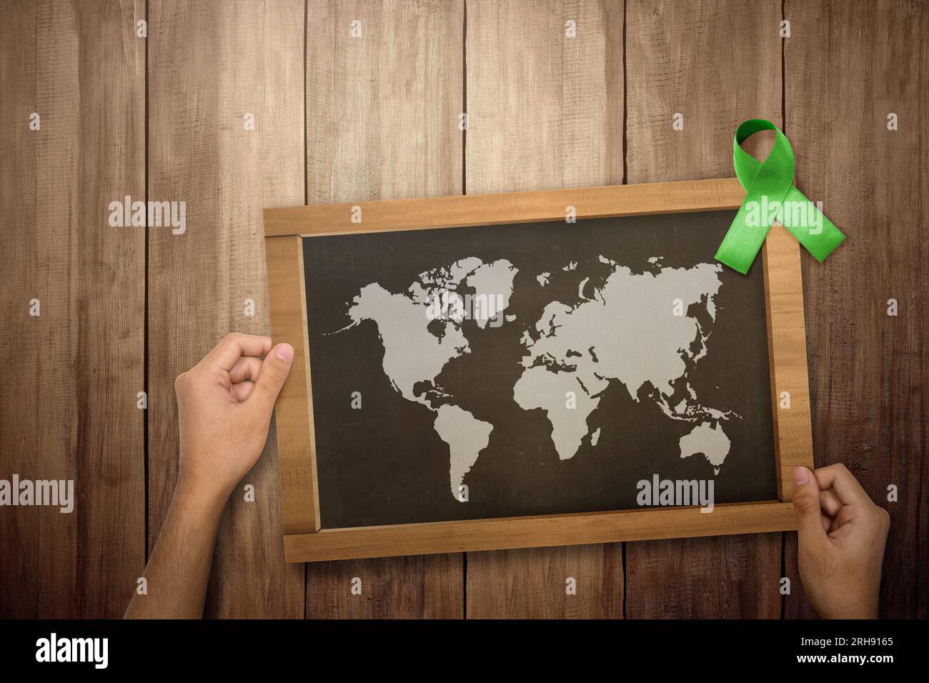 Green ribbon and blackboard with worldwide map. World mental health day ...