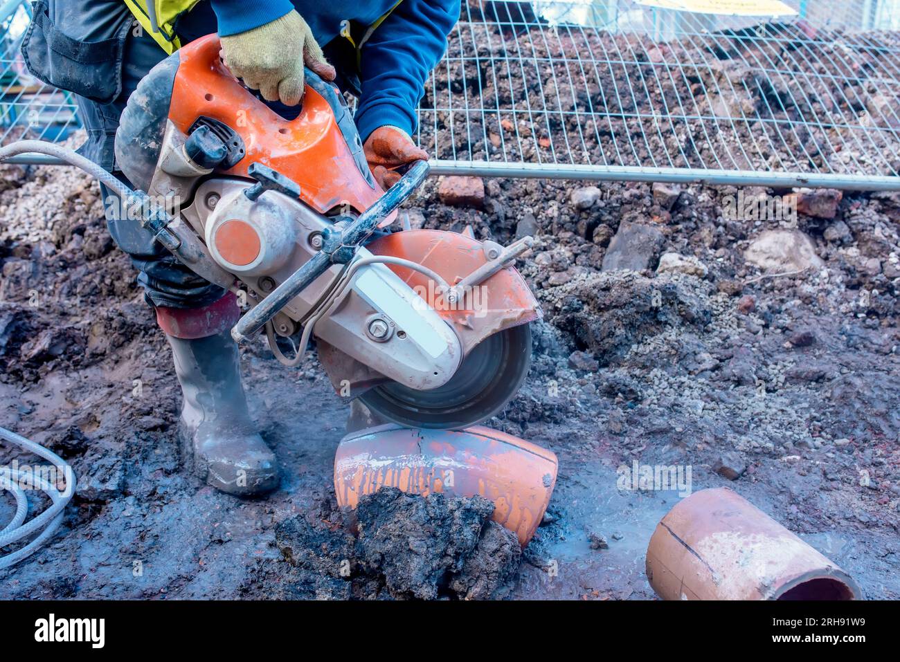 Builder cutting clay pipe with petrol concrete saw and a diamond