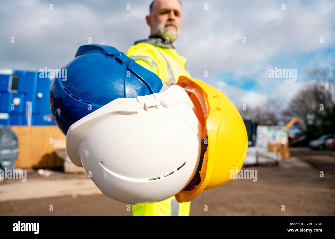 A builder wearing a hiviz reflective suit gives a choice of helmets